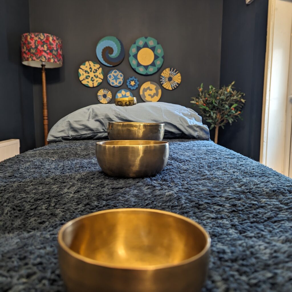 A picture of a massage bed with blankets and sound bowls ready for a holistic treatment